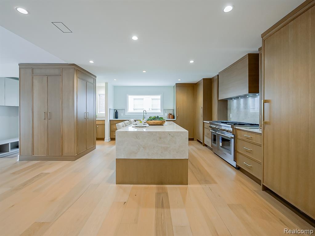 Kitchen featuring double oven range, a center island, light wood finished floors, custom exhaust hood, and recessed lighting