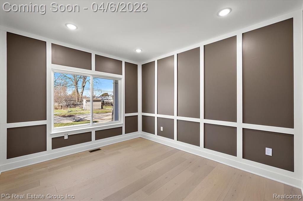 Unfurnished room with a decorative wall, light wood-style flooring, and recessed lighting