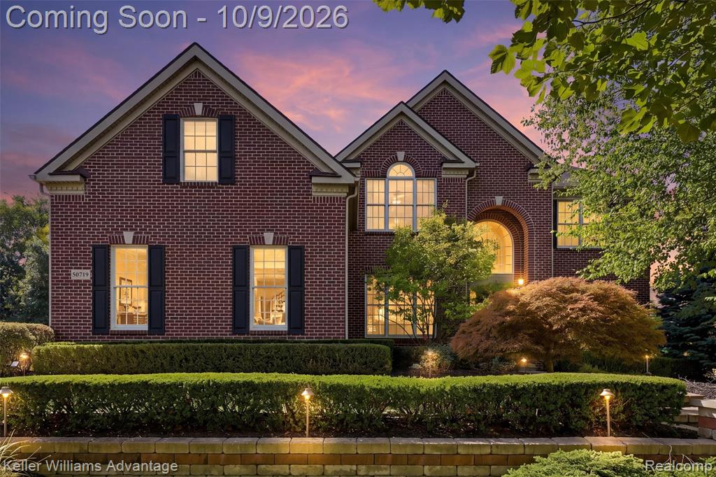 Brick exterior with white window trim, black louvered shutters, and a prominent arched entryway