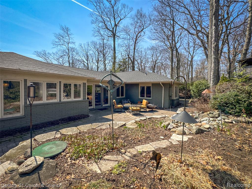 Rear view of house featuring brick siding, a patio area, a shingled roof, and outdoor seating