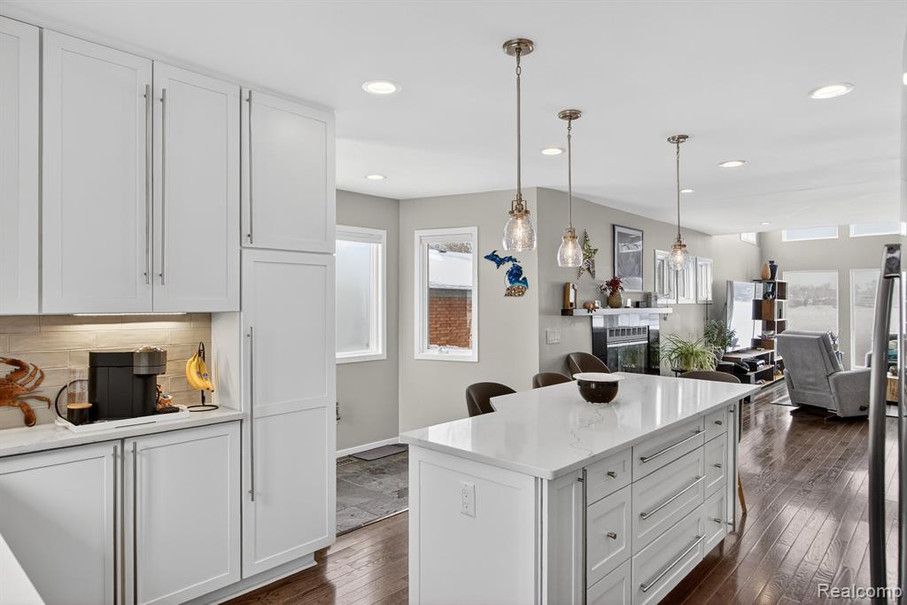 Kitchen with a breakfast bar area, white cabinetry, decorative light fixtures, and recessed lighting