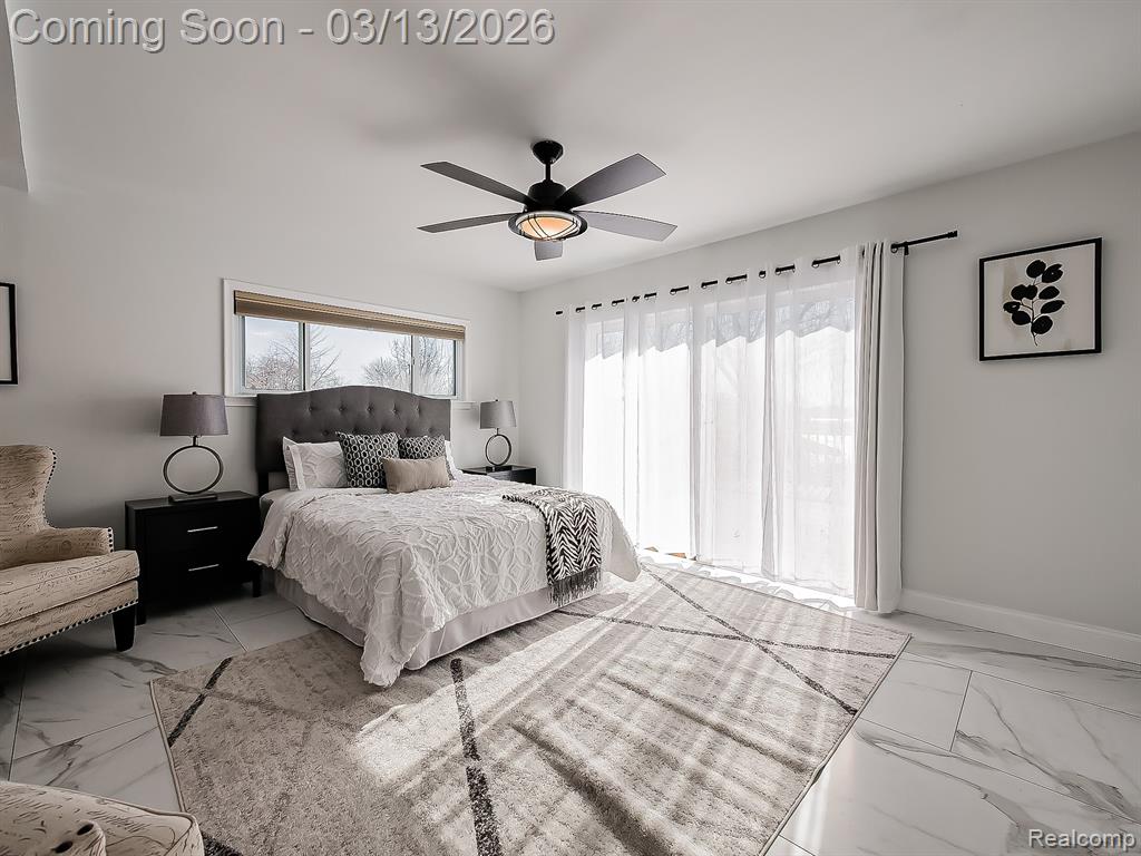 Bedroom featuring a barn door, marble look tiles, and ceiling fan