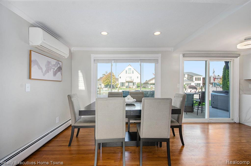 Dining room with baseboard heating, wood finished floors, ornamental molding, and recessed lighting