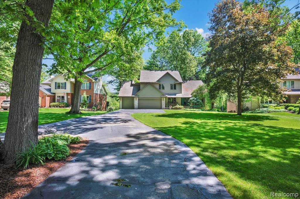Spacious property with a multi-level residence featuring a neutral-toned exterior and a dark asphalt driveway