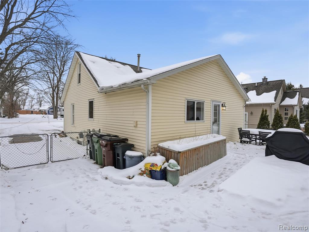 Snow covered property with a gate, a deck, and outdoor dining space