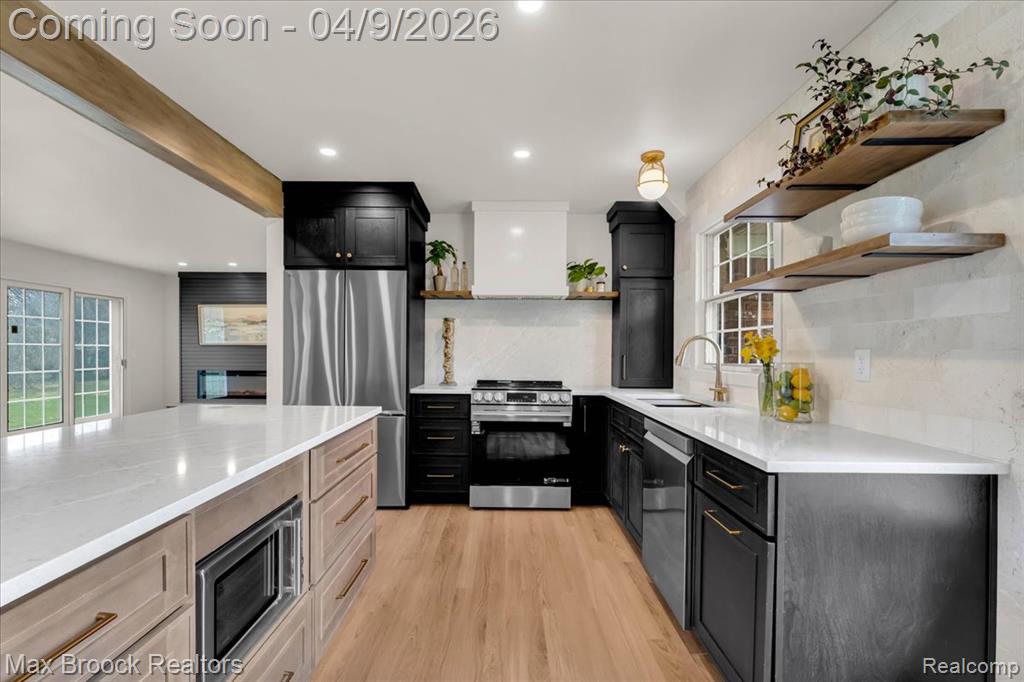 Kitchen featuring open shelves, light stone counters, stainless steel appliances, light wood-type flooring, and tasteful backsplash