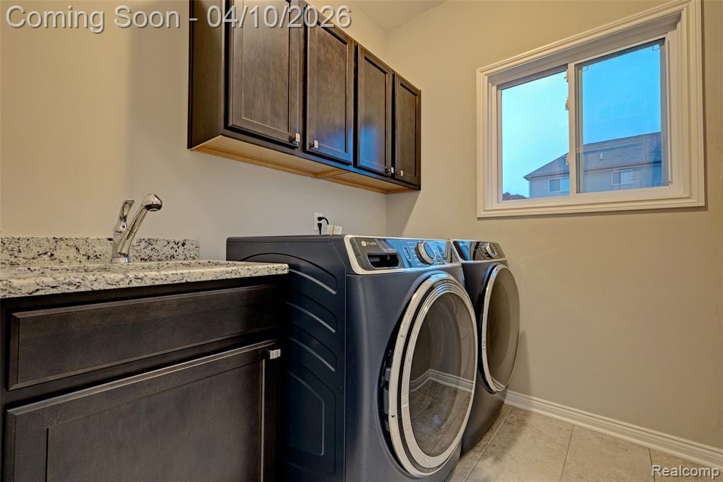 Laundry room with cabinet space, washing machine and dryer, and light tile patterned floors