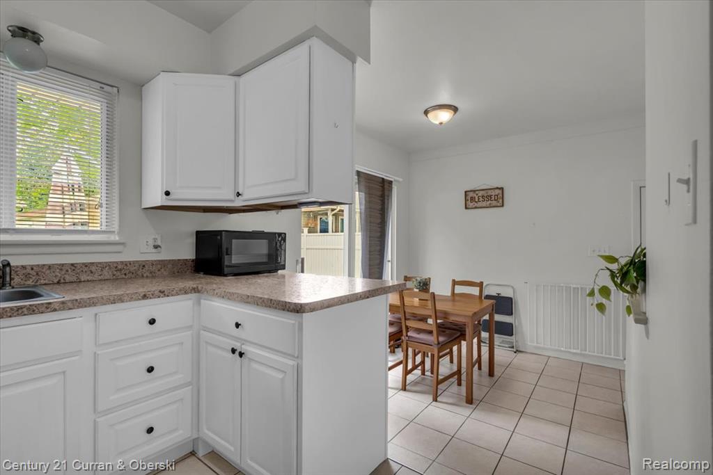 Kitchen with white cabinetry, light tile patterned floors, a peninsula