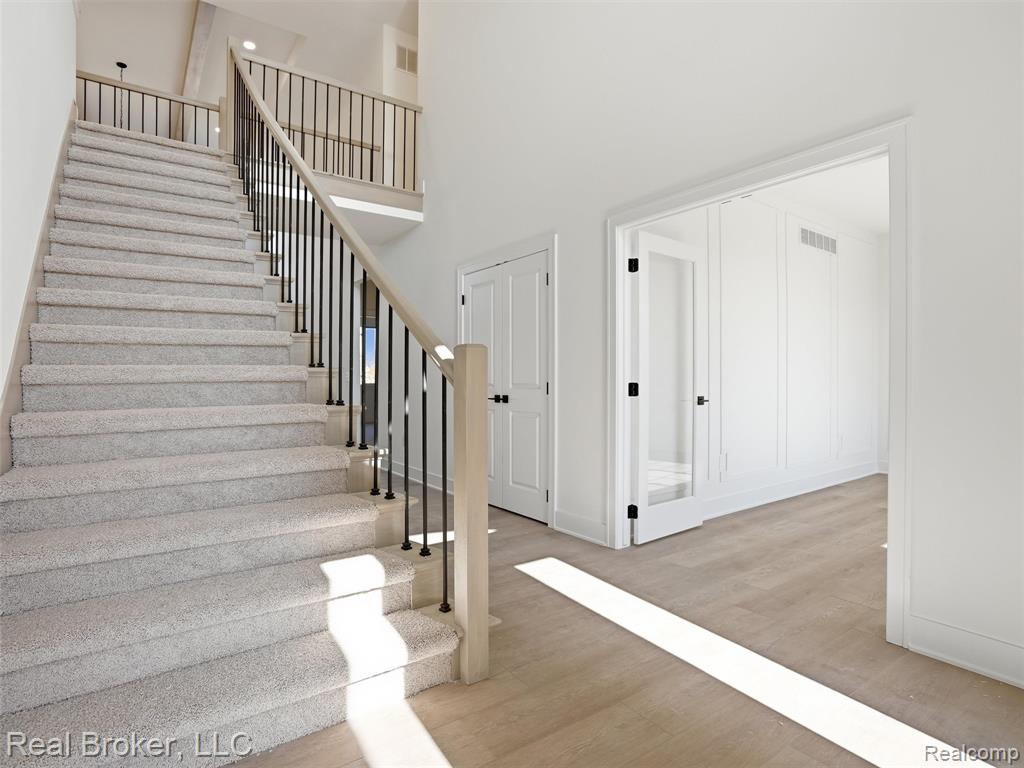 Staircase with wood finished floors and a high ceiling