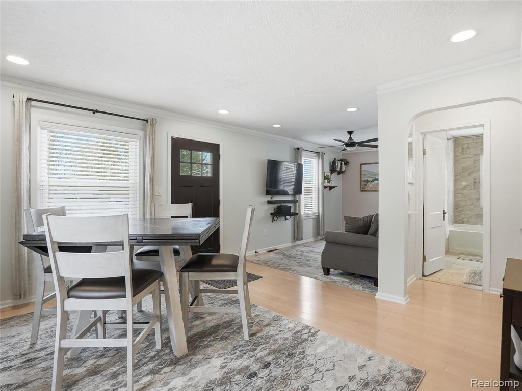 Dining area with light wood-style floors, ornamental molding, recessed lighting, a ceiling fan, and a textured ceiling