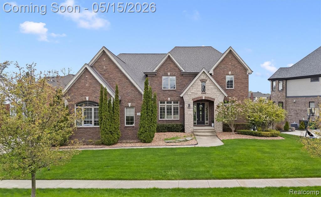 View of front of house with a front yard, brick siding, and stone siding