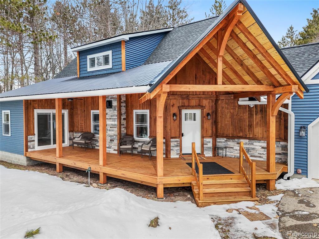 View of front facade featuring a metal roof, board and batten siding, a shingled roof, and a deck