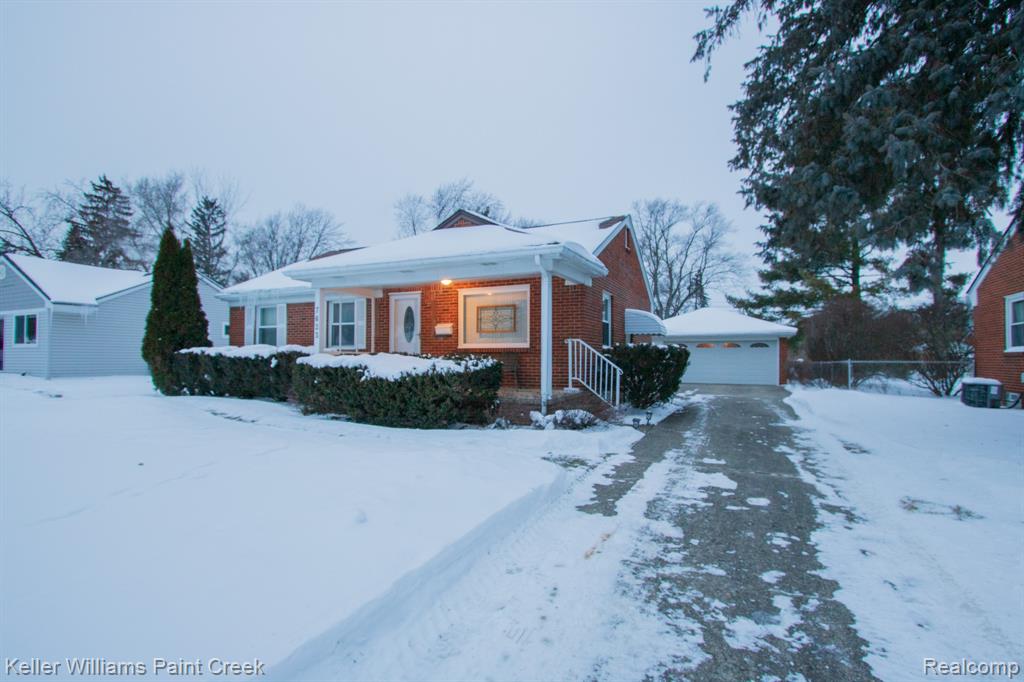 View of front of home featuring brick siding, an outbuilding, a garage, and a porch