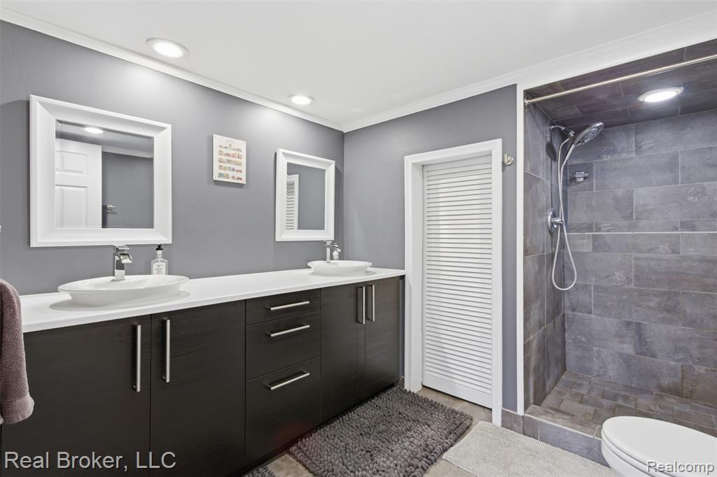 Bathroom featuring double vanity, a stall shower, recessed lighting, and crown molding