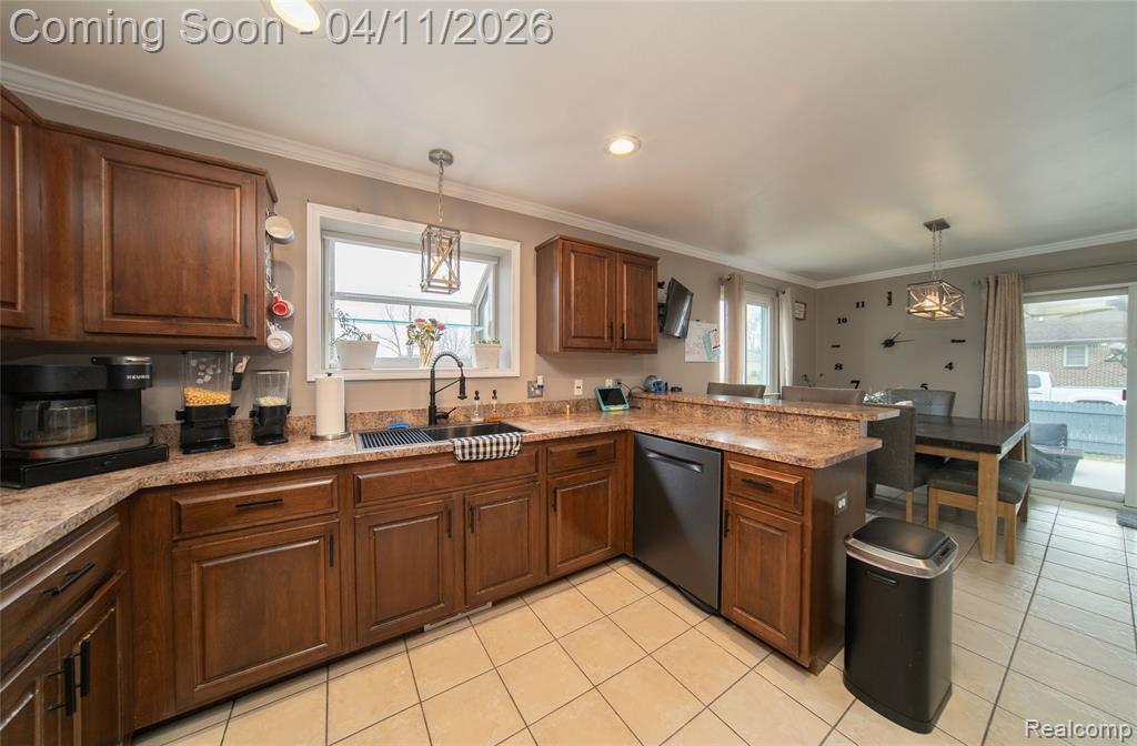 Kitchen featuring a peninsula, decorative light fixtures, crown molding, dishwasher, and healthy amount of natural light