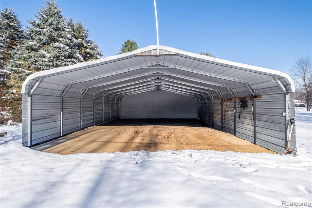 Snow covered parking area featuring a carport