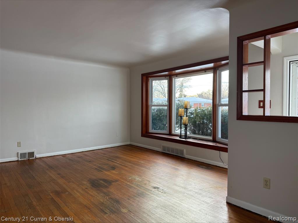 Spare room featuring dark wood-style floors and baseboards