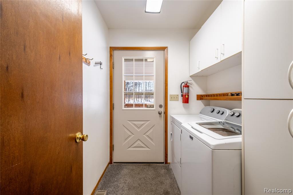Laundry room featuring cabinet space, washing machine and clothes dryer, and dark colored carpet