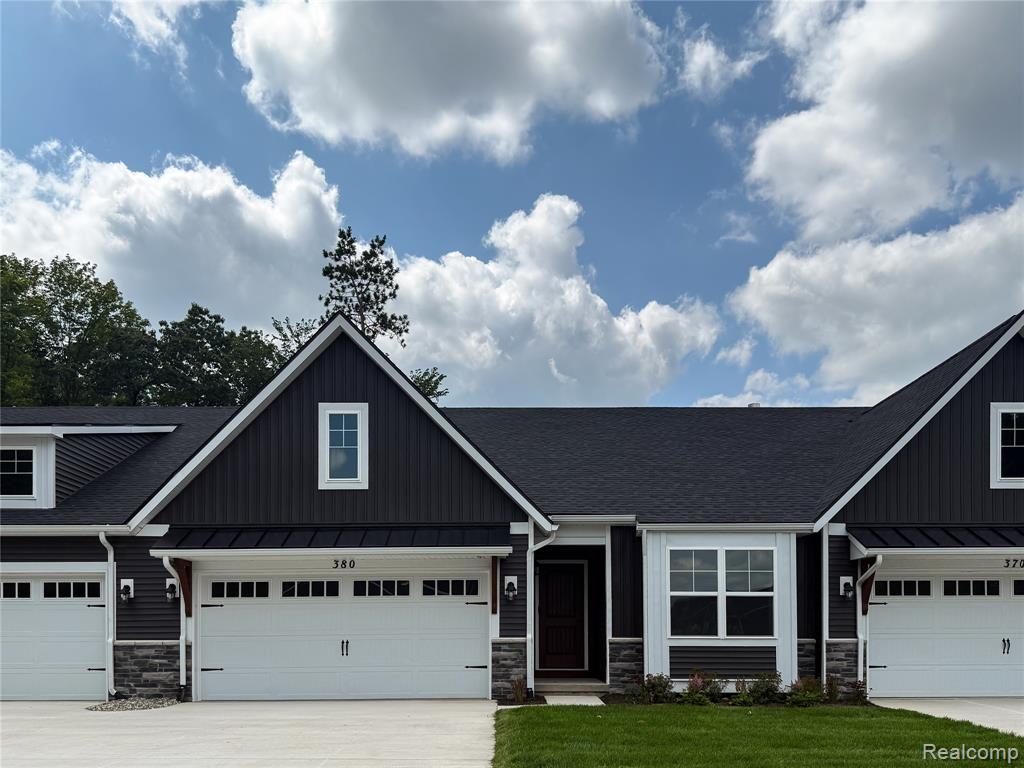 Dark-toned exterior siding with white trim, a gabled roofline, and an attached garage with a white overhead door