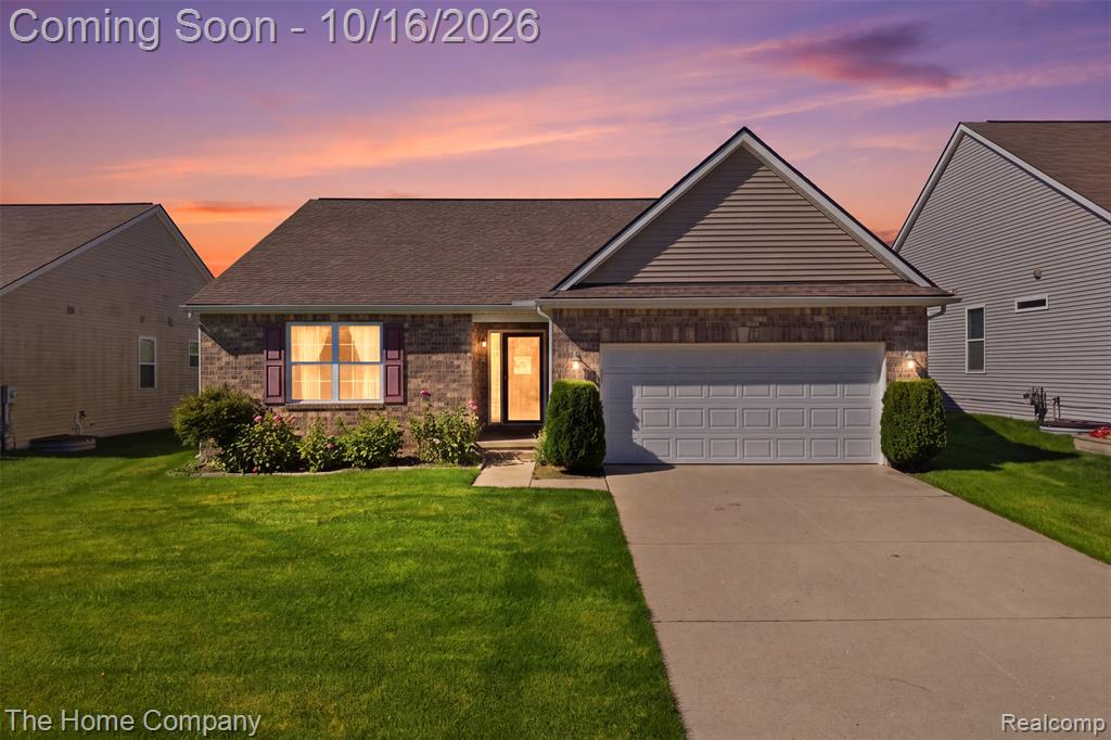 Single-story residence featuring a brick and vinyl-sided exterior, front-facing two-car garage, concrete driveway, and gabled roofline