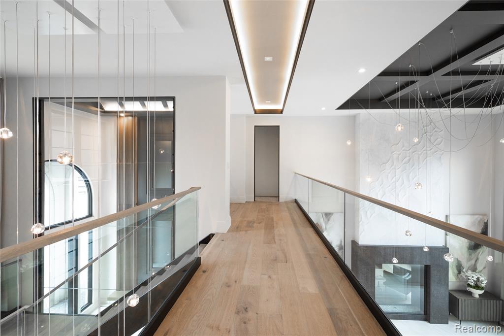 Hall featuring light wood-style flooring, an upstairs landing, and recessed lighting