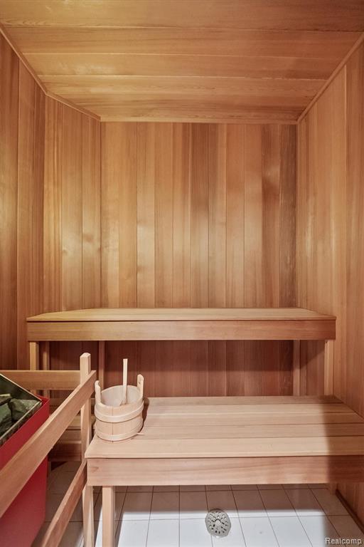 Relaxing sauna featuring tile patterned flooring, wooden ceiling, and wooden walls