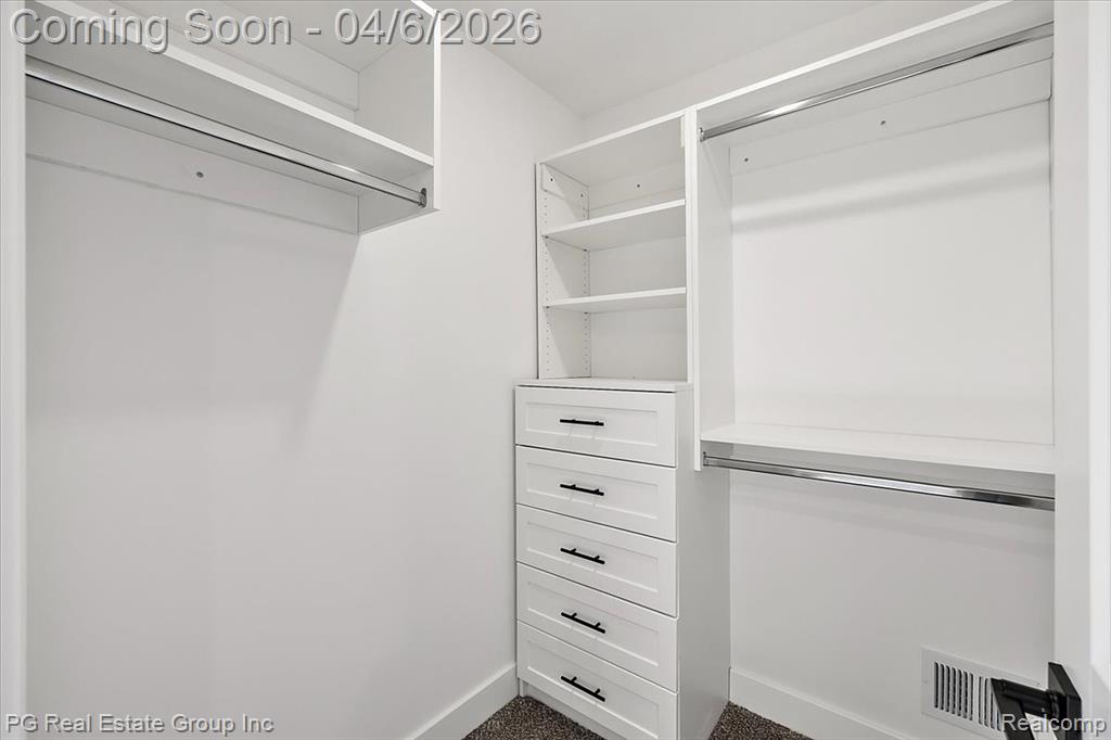 Walk in closet featuring dark colored carpet