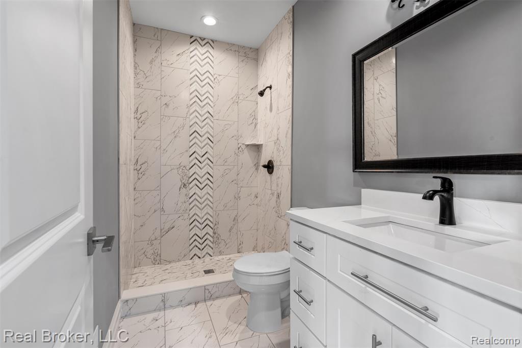 Full bath with vanity, light marble finish flooring, and a shower stall