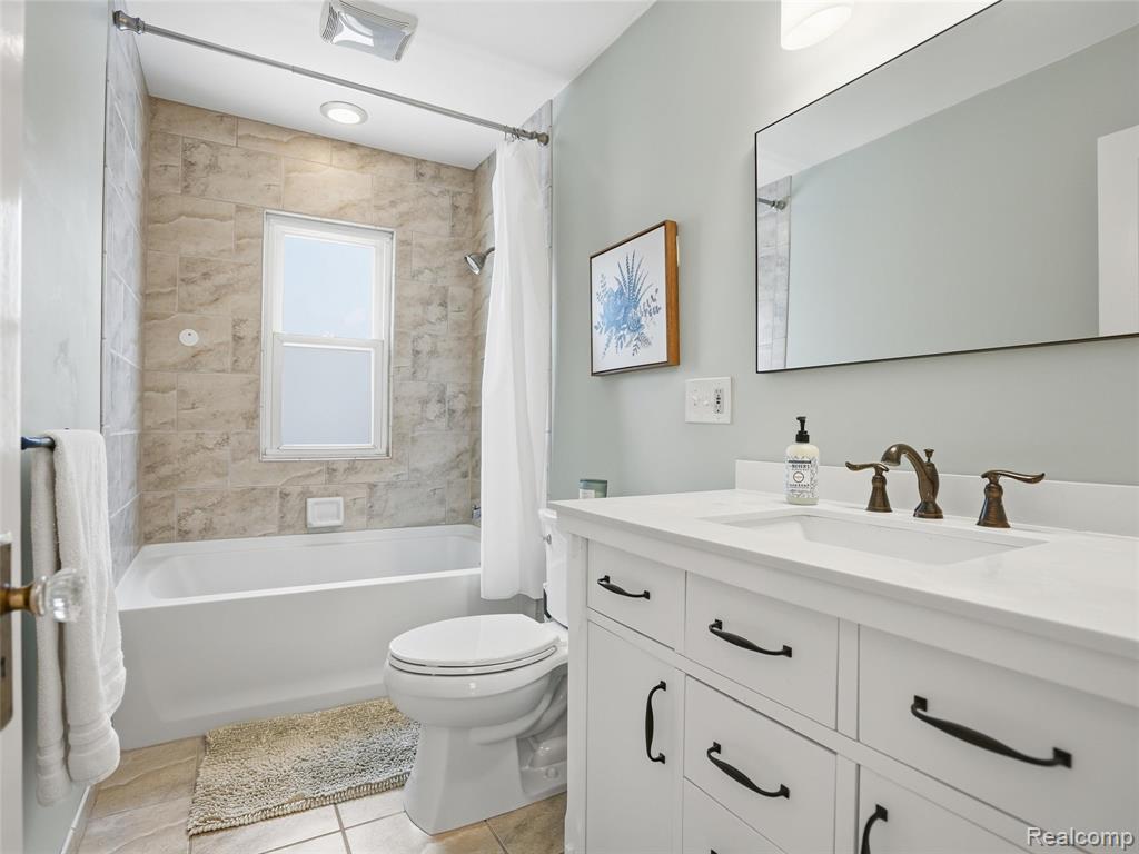 Bathroom featuring vanity, shower / tub combo with curtain, and light tile patterned flooring