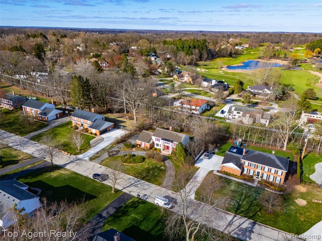Aerial perspective of suburban area featuring a nearby body of water and a golf course