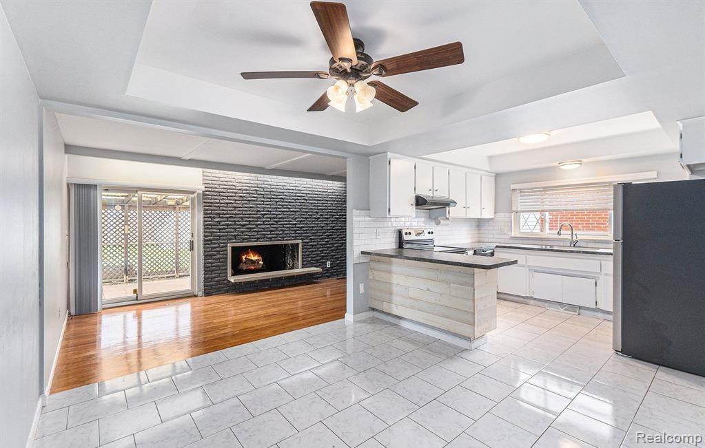 Kitchen featuring a raised ceiling, open floor plan, white cabinets, and a peninsula