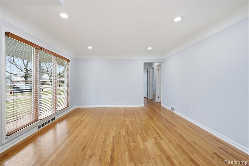 Empty room with light wood-style floors and recessed lighting