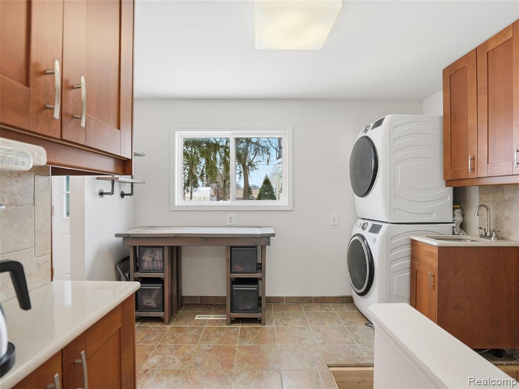 Laundry room with stacked washer and clothes dryer and cabinet space