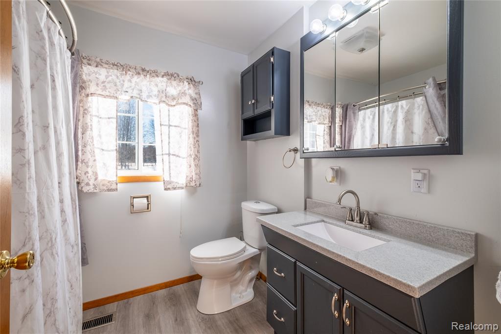Bathroom with vanity, curtained shower, and light wood finished floors