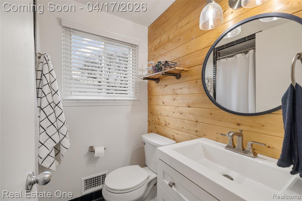 Full bathroom with vanity, wood walls, and a shower with shower curtain