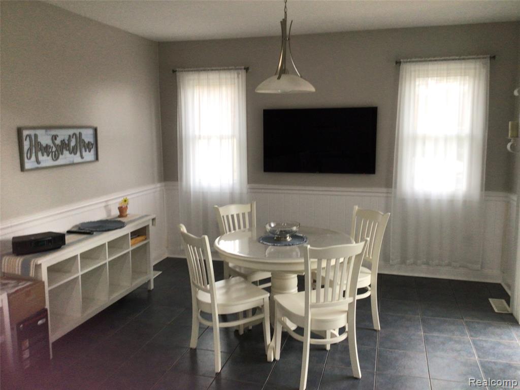 Dining area with wainscoting and dark tile patterned flooring