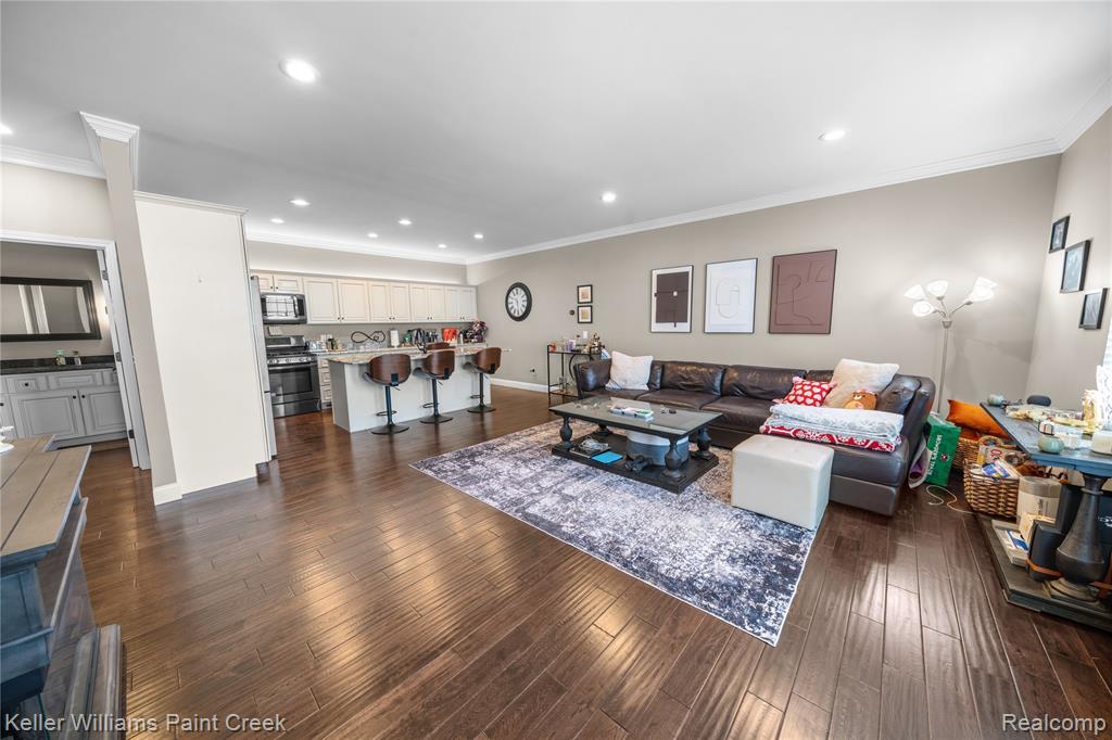Living room with dark wood-type flooring, crown molding, and recessed lighting