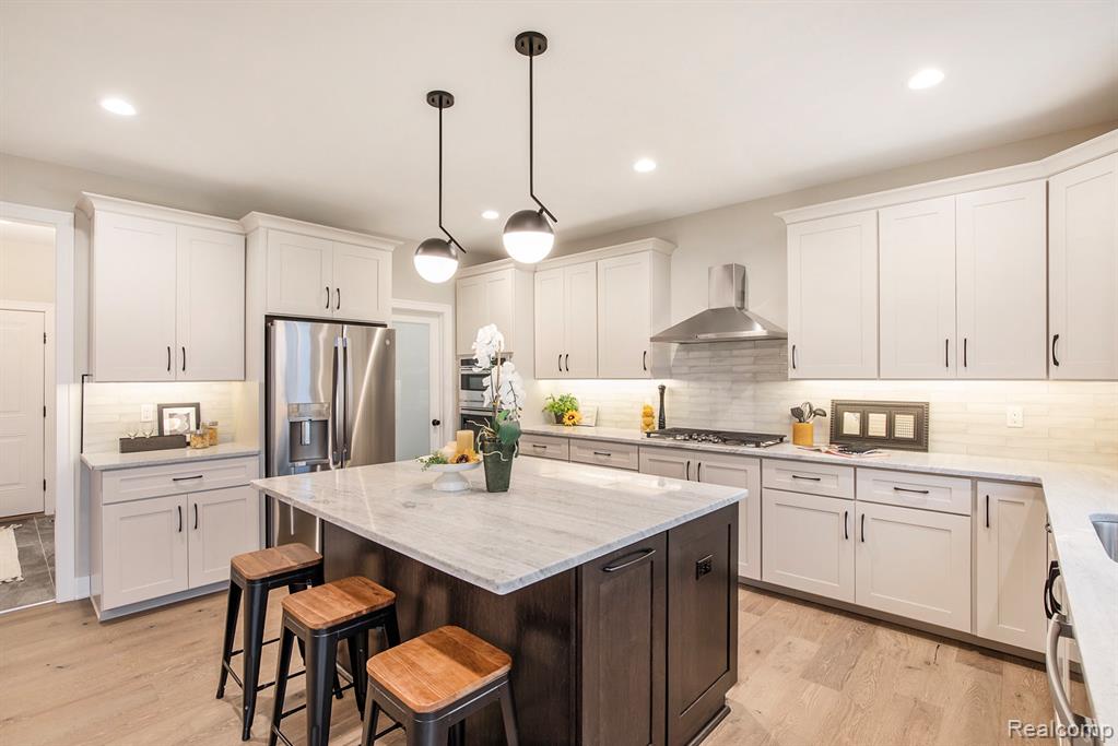 Kitchen featuring dark brown cabinetry, light stone countertops, decorative light fixtures, a breakfast bar area, and a center island