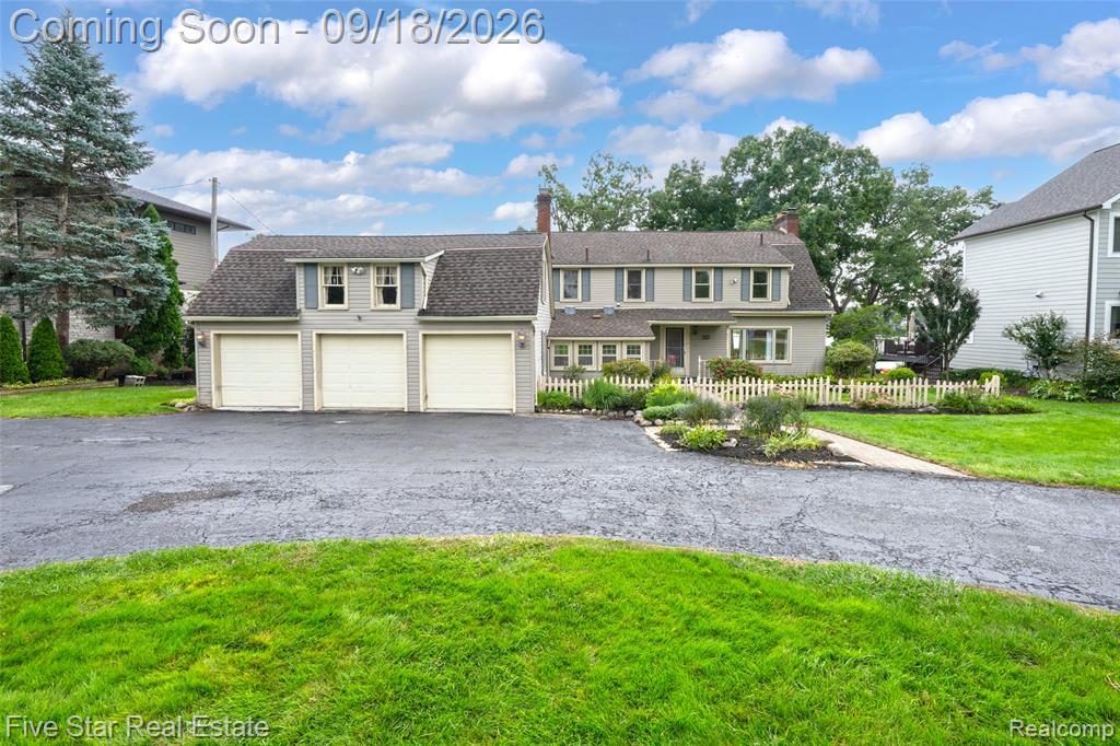 Two-story residence with a three-car garage, dormer windows, and a picket fence