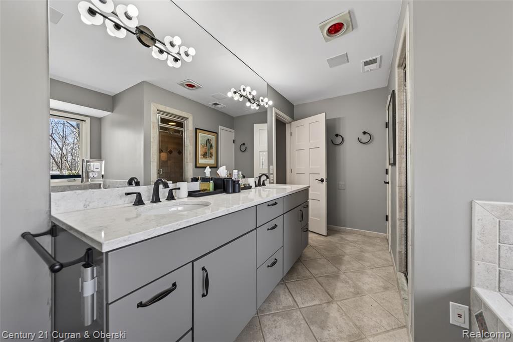 Full bathroom with double vanity, a stall shower, and light tile patterned floors