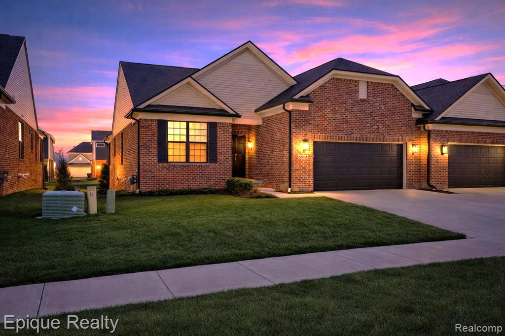 View of front of home with a lawn, a garage, driveway, and brick siding