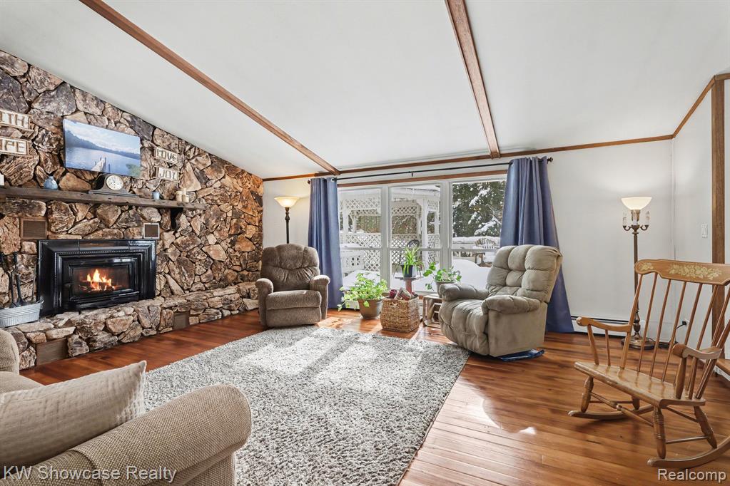Living area with hardwood / wood-style floors, a fireplace, and lofted ceiling with beams