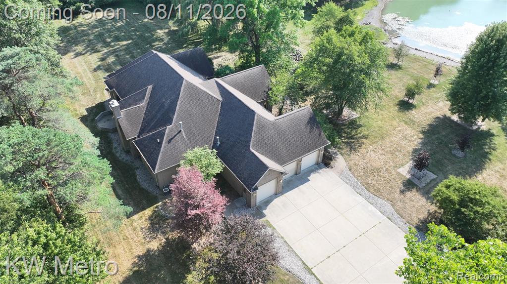 Expansive property featuring a multi-gabled roofline, a two-car garage, a concrete driveway, and direct water access