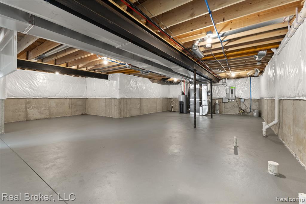 Unfinished basement featuring heating unit, water heater, and electric panel