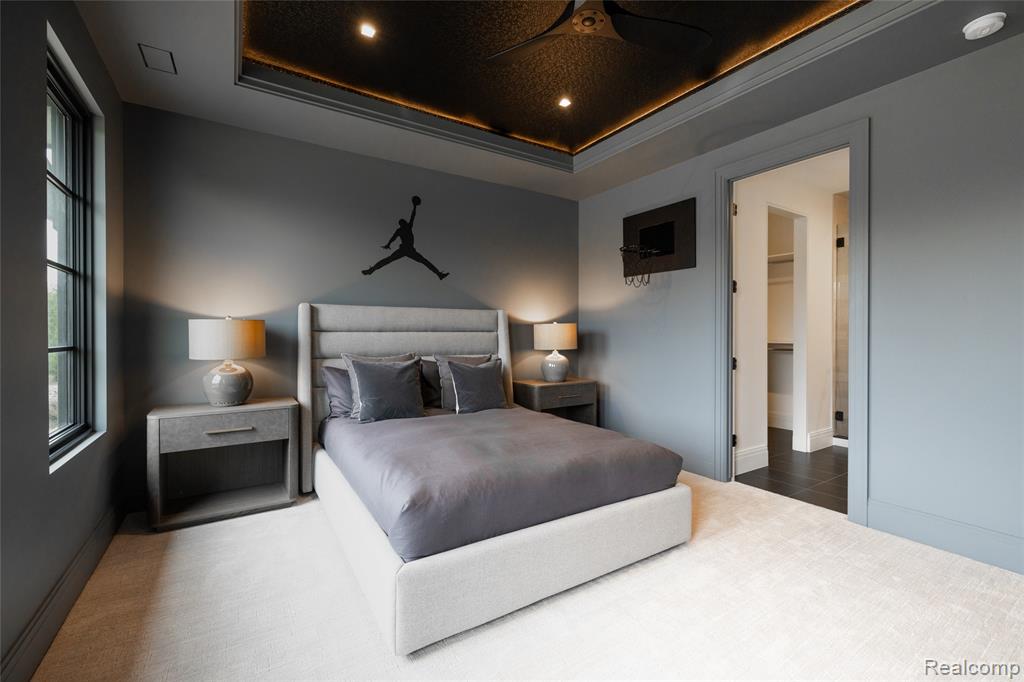 Bedroom featuring a tray ceiling, recessed lighting, ceiling fan, and ensuite bathroom