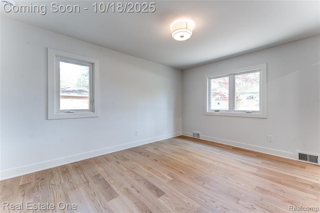 Unfurnished room with light wood finished floors and healthy amount of natural light