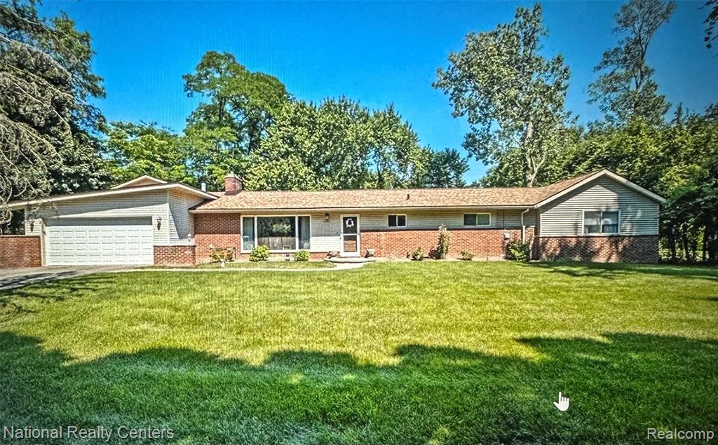Single story home with an attached garage, a front lawn, and brick siding