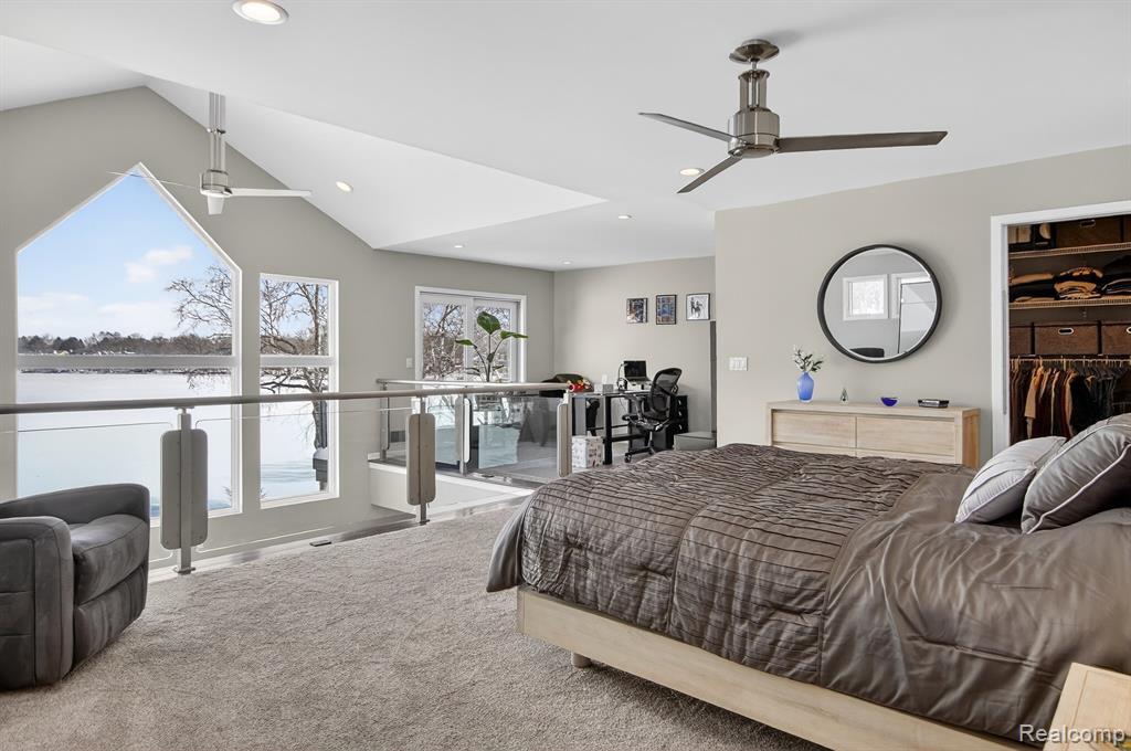 Carpeted bedroom featuring vaulted ceiling, an office area, a spacious closet, ceiling fan, and recessed lighting
