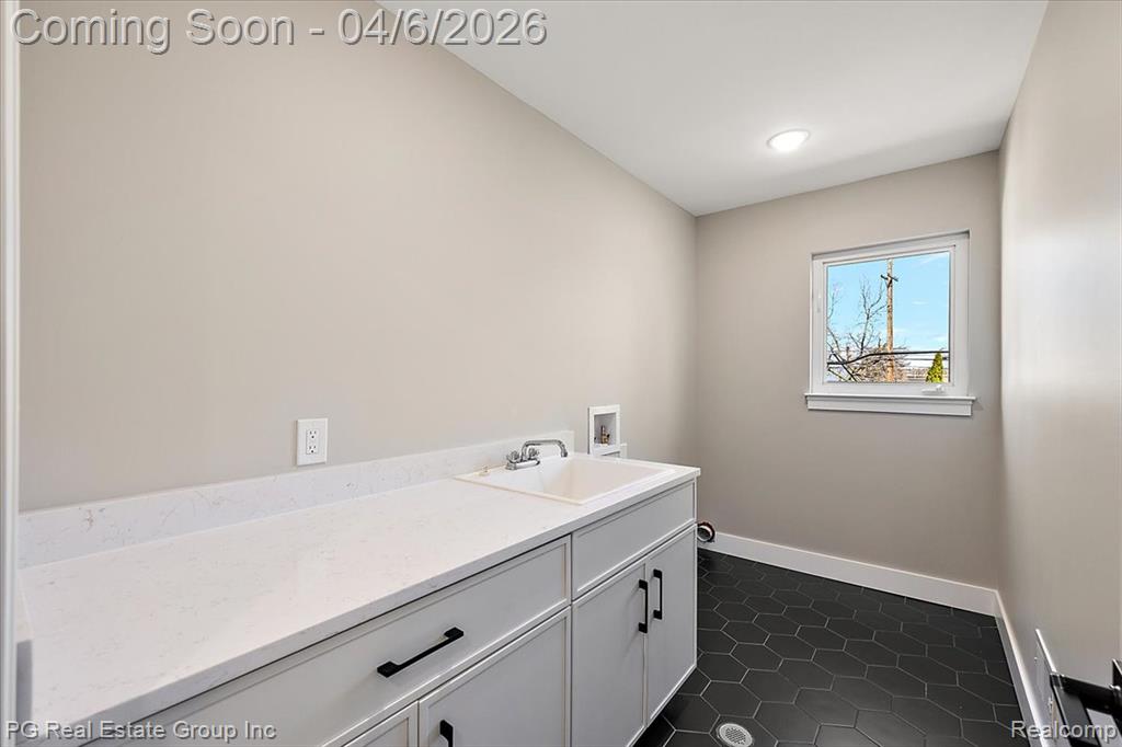 Laundry room with washer hookup, dark tile patterned flooring, and cabinet space