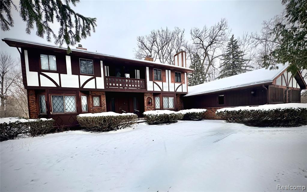 Back of property featuring a balcony, a chimney, a lawn, and stucco siding